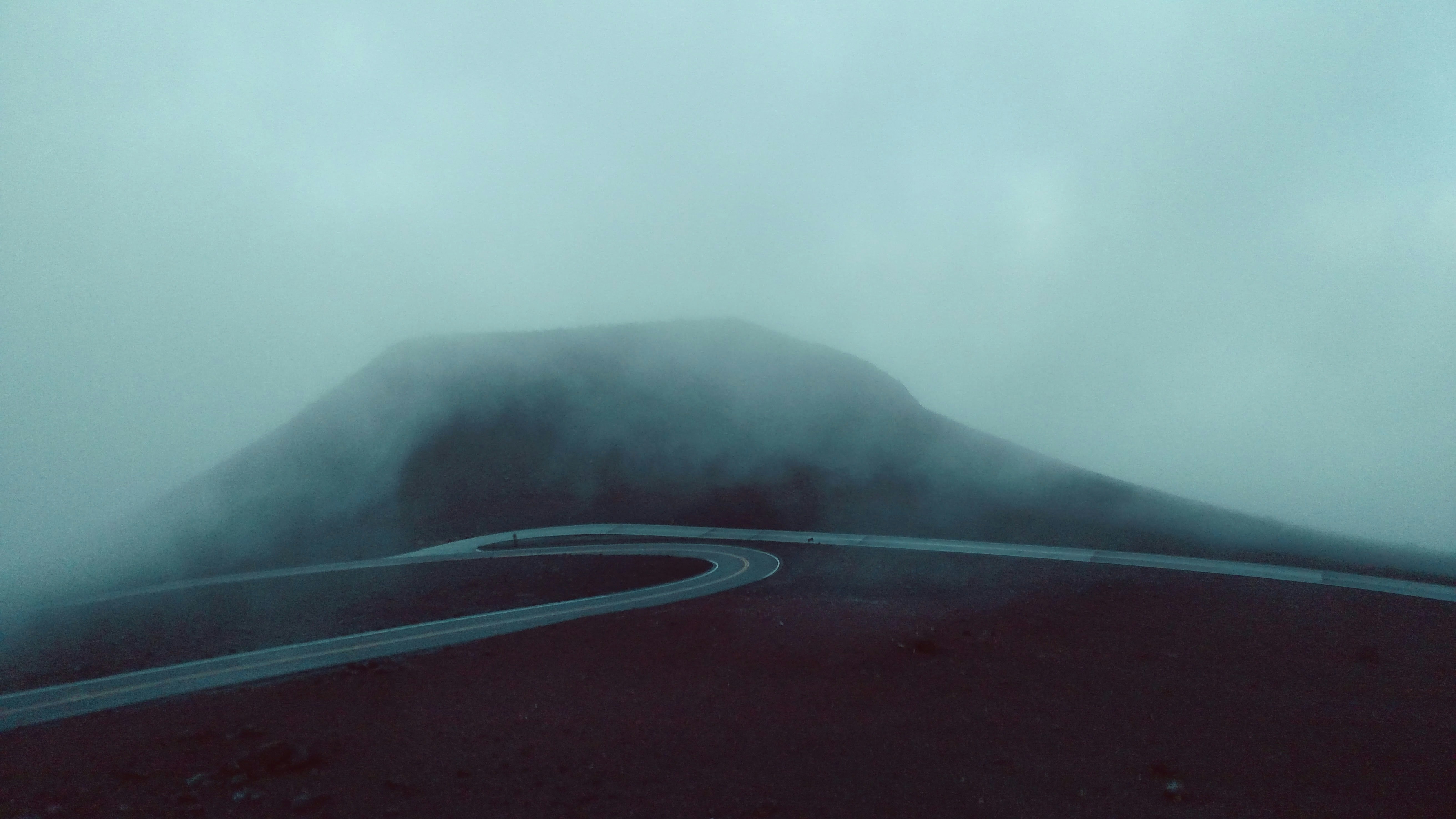 concrete road near mountain during foggy weather